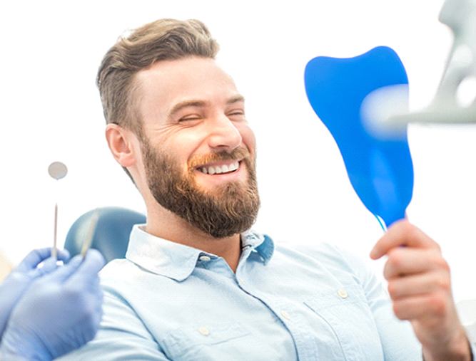 Man smiling while looking in his dentist's mirror