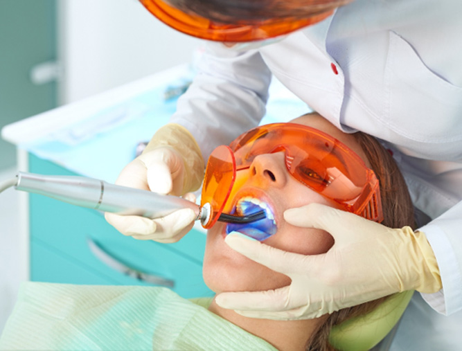 A dentist giving a tooth-colored filling to a young woman