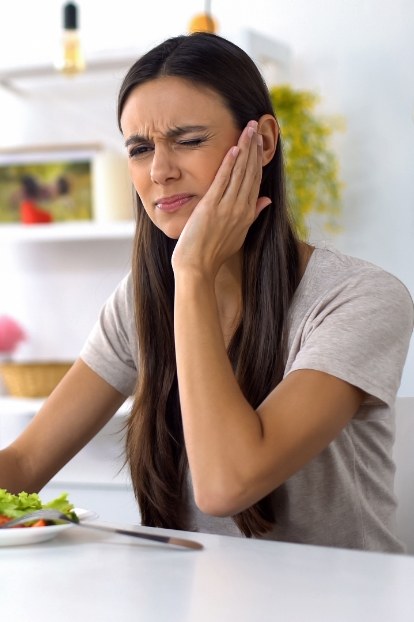 Woman in need of emergency dentistry holding her jaw