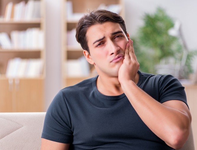 Man in need of emergency dentistry holding jaw