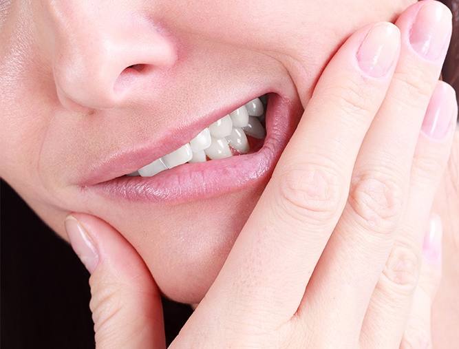 Person in pain before tooth extraction holding jaw