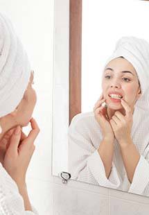 Woman looking at her teeth in bathroom mirror