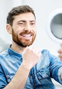 Patient smiling while looking in dental mirror