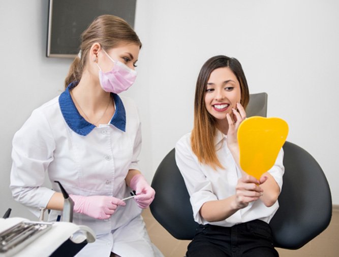Satisfied patient admiring the results of her smile makeover