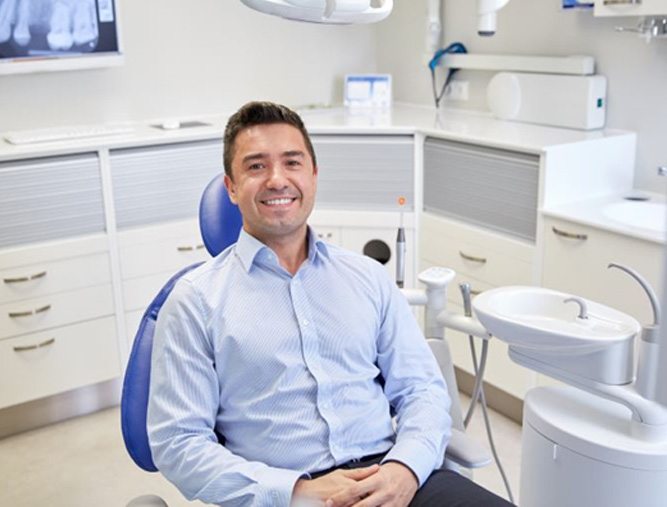Happy dental patient in treatment chair after dental implant salvage