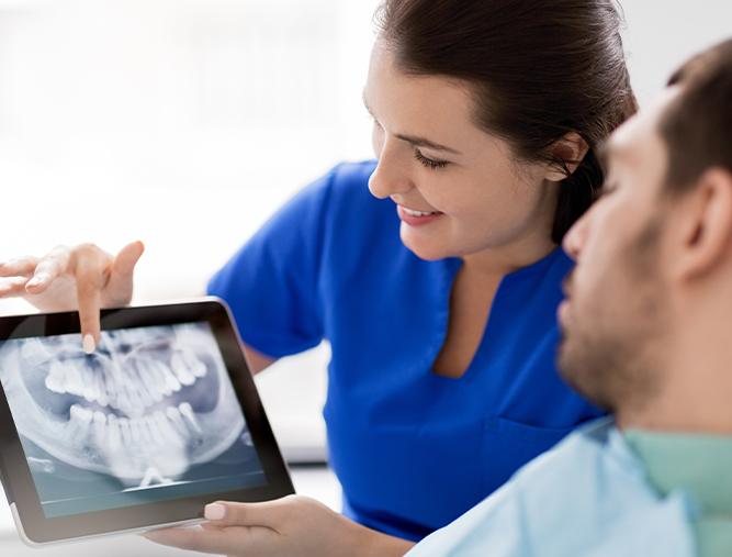 Dental team member and patient examining digital x-rays