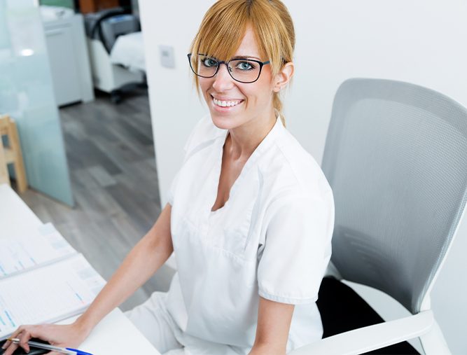 Dental team member smiling behind reception desk