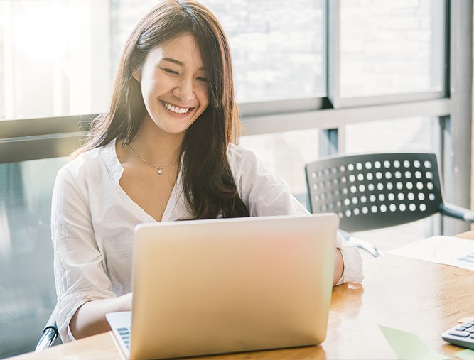 Woman with porcelain vneeers smiling and looking at her laptop