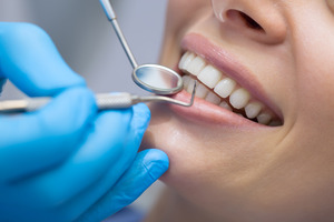 Close-up of dentist examining and cleaning patient’s teeth