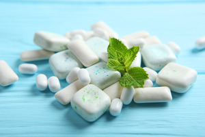 Chewing gum and breath mints in a pile with an herb